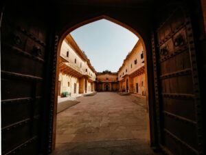 View through a grand arched gate into a historic courtyard in Jaipur, India.
